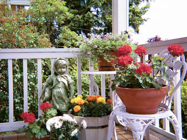 Front porch decorated with flowers and statues - Gitta Sells